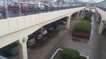 Two-story car park with a three-lane road in the background.