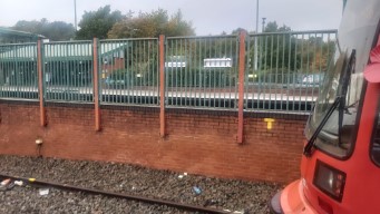 Tram tracks, a fence, train tracks.